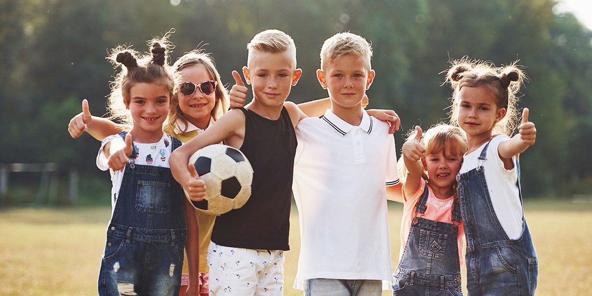 Young sportive kids with soccer ball stands together in the fiel